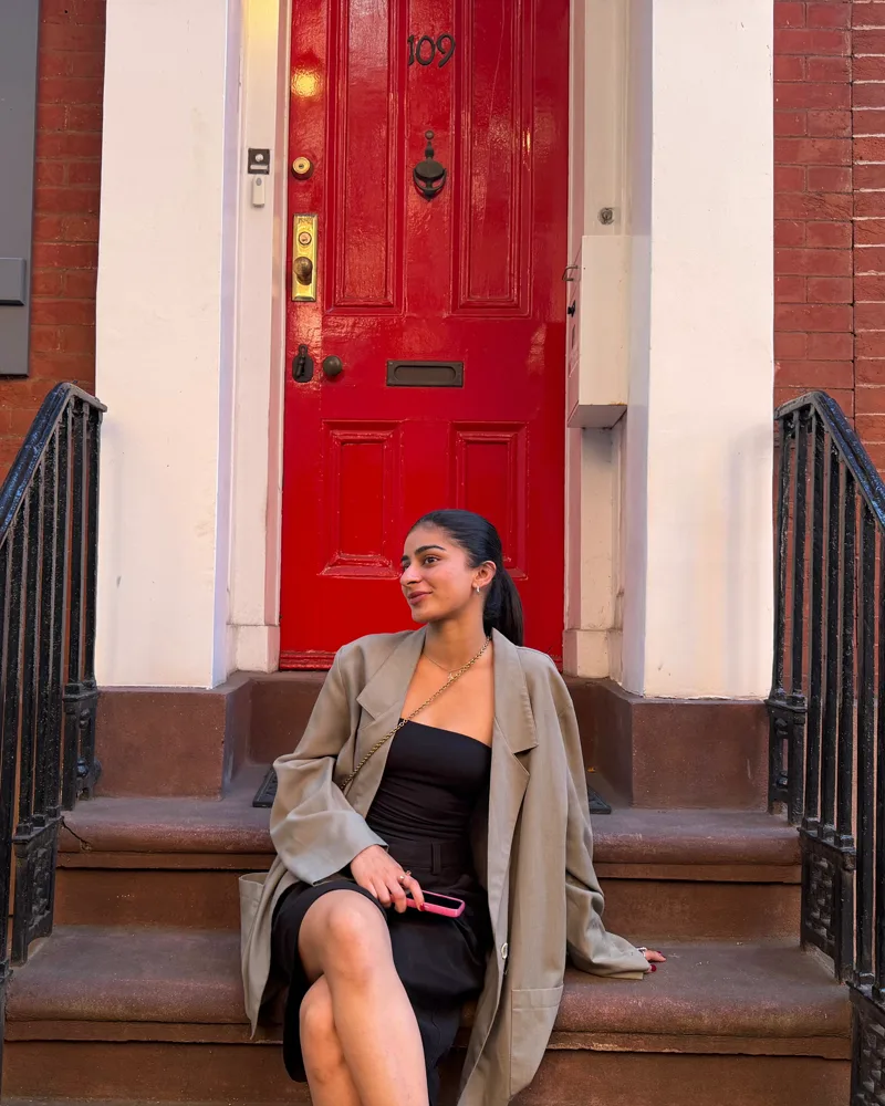 Eman, Kojey's director, seated on brownstone steps in front of a red door